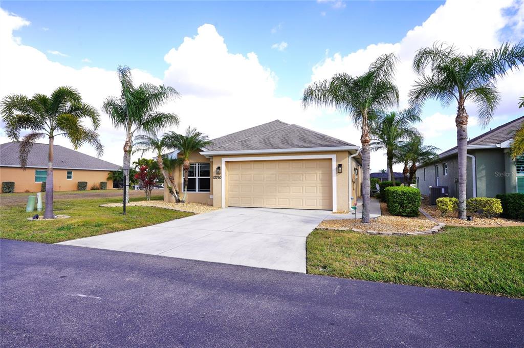 A beige single-story house with a two-car garage and palm trees in the front yard — 12760 SW LAKE SIDE DRIVE, ARCADIA, FL