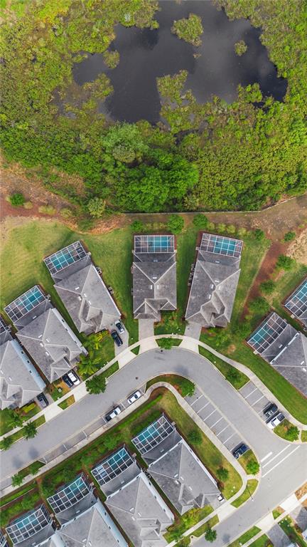 An aerial view shows a suburban cul-de-sac with houses featuring screened-in pools near a pond — 1571 PALMERO WAY, CHAMPIONS GATE, FL