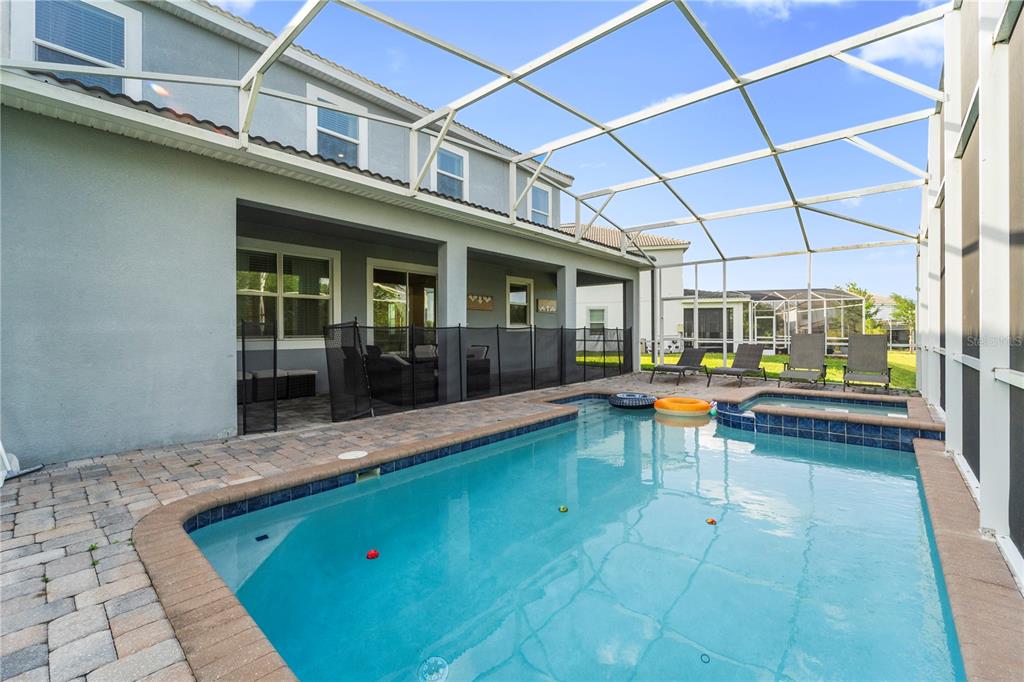 A screened-in patio features a swimming pool, a hot tub, and a paved deck — 1571 PALMERO WAY, CHAMPIONS GATE, FL