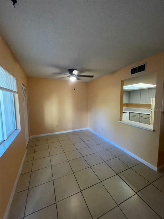 An empty room with light-colored floor tiles, peach walls, a ceiling fan, and a pass-through — 549 FAIRWAYS DRIVE UNIT A, OCALA, FL