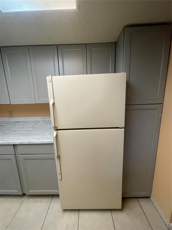 A kitchen features gray cabinets, a white refrigerator, and a light-colored countertop — 549 FAIRWAYS DRIVE UNIT A, OCALA, FL