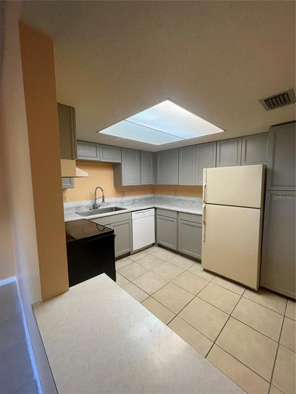 A kitchen features gray cabinets, light countertops, a white dishwasher, and a beige refrigerator — 549 FAIRWAYS DRIVE UNIT A, OCALA, FL
