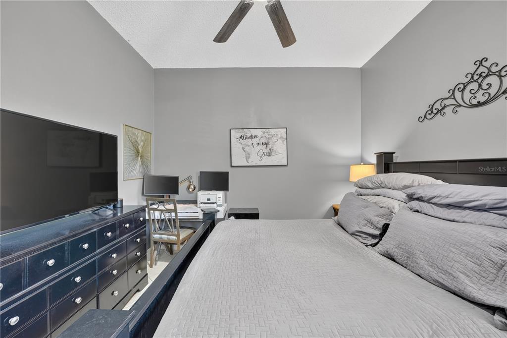A bedroom with a dark wood bed frame, gray walls, a ceiling fan, and a desk — 13686 CRYSTAL RIVER DRIVE, ORLANDO, FL