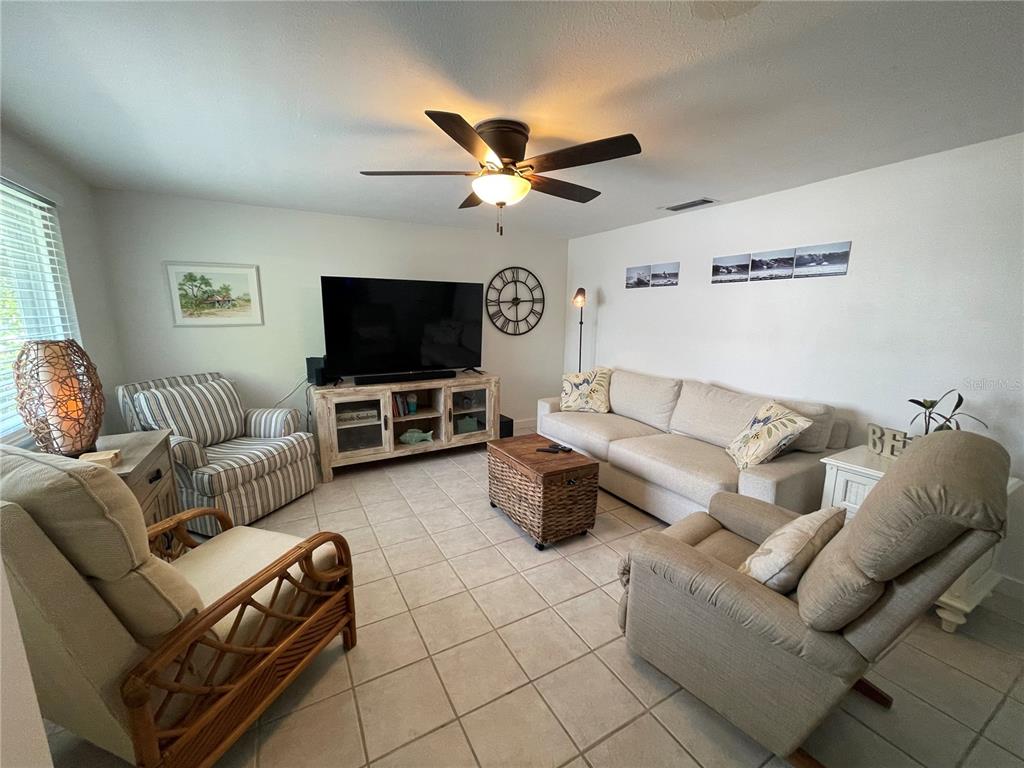 A living room features a television on a wooden console, a sofa, and armchairs — 2904 AVENUE B, BRADENTON BEACH, FL