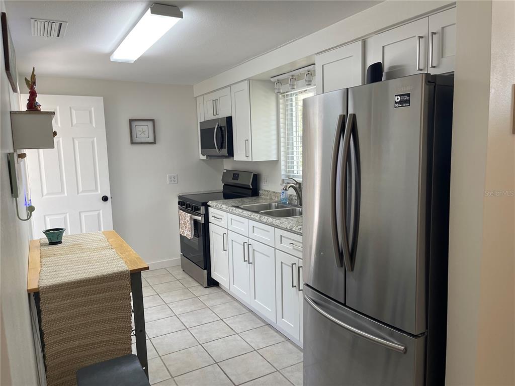A living room features tile flooring, a ceiling fan, a television console, and neutral seating — 2904 AVENUE B, BRADENTON BEACH, FL