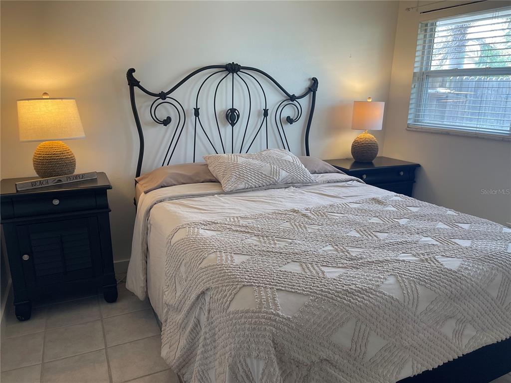 A bedroom features a black metal bed frame, two matching nightstands, and textured bedding — 2904 AVENUE B, BRADENTON BEACH, FL