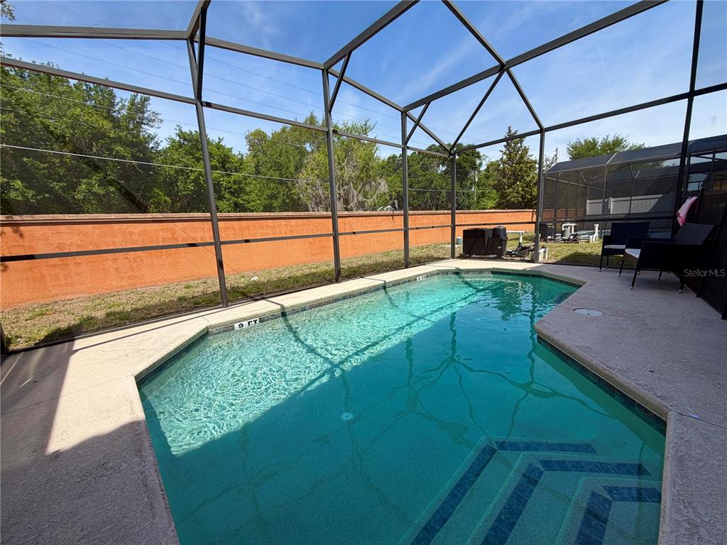 A living room features a black sectional sofa, a television on a wood-paneled wall, and dining area — 720 LAS FUENTES DRIVE, KISSIMMEE, FL