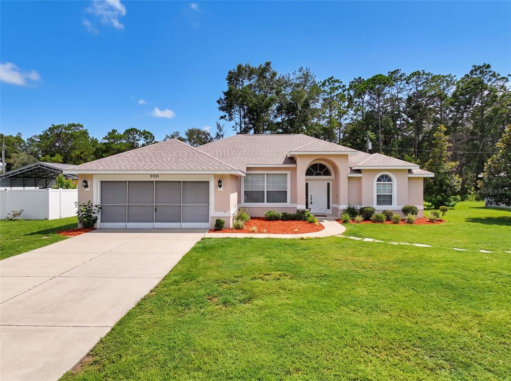 A single-story house with a beige exterior, a two-car garage, and a landscaped front yard — 9700 N KENDALL WAY, CITRUS SPRINGS, FL