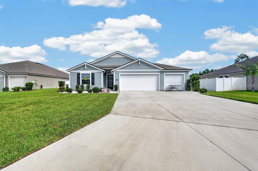 A single-story house with light blue siding, a three-car garage, and a concrete driveway — 81 HICKORY RIDGE ROAD, ST AUGUSTINE, FL