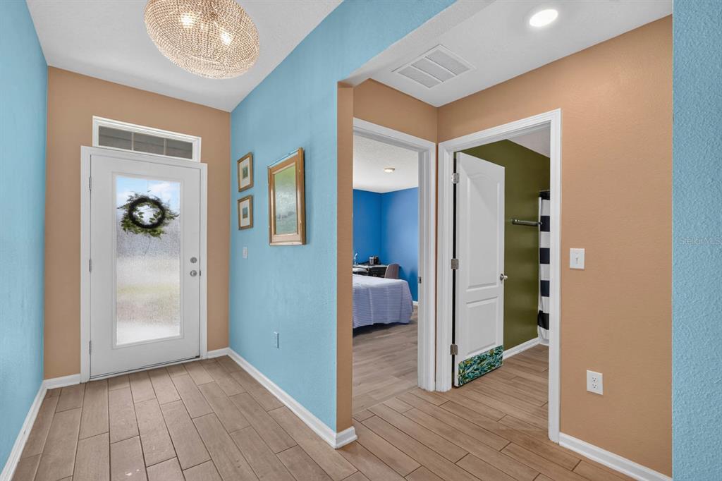 An entryway with light blue and tan walls, wood-look tile flooring, and a glass-paneled door — 81 HICKORY RIDGE ROAD, ST AUGUSTINE, FL