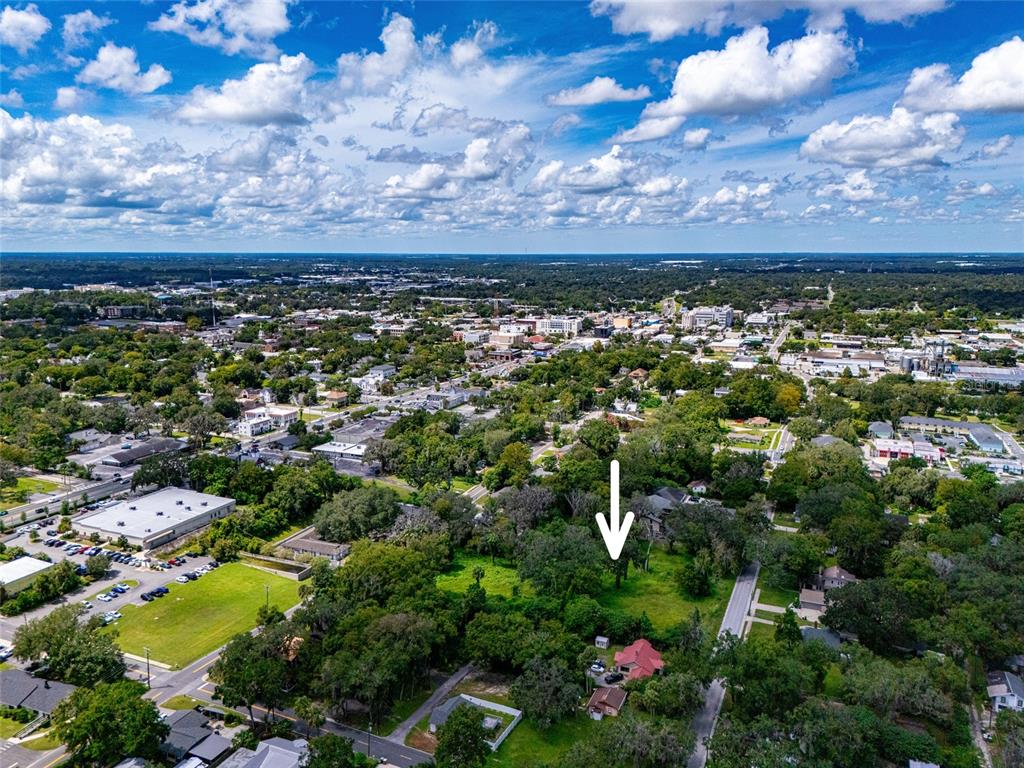 An aerial view shows a wooded lot with a white arrow pointing toward the center — 9TH AVE, OCALA, FL