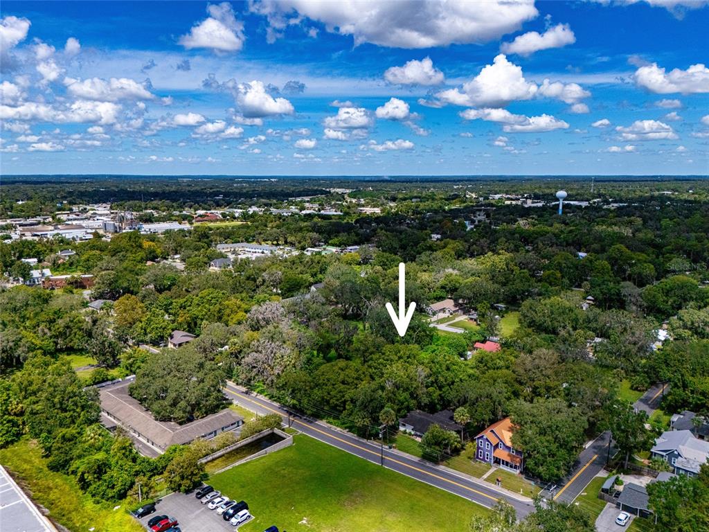 An aerial view shows a wooded lot with a house and nearby commercial buildings — 9TH AVE, OCALA, FL