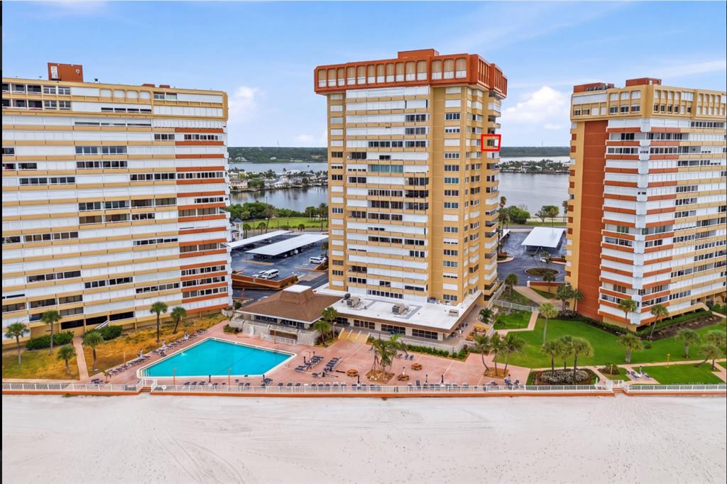 An aerial view shows three tall apartment buildings situated on a sandy beach with pools — 17920 GULF BOULEVARD UNIT 1502, ST PETERSBURG, FL