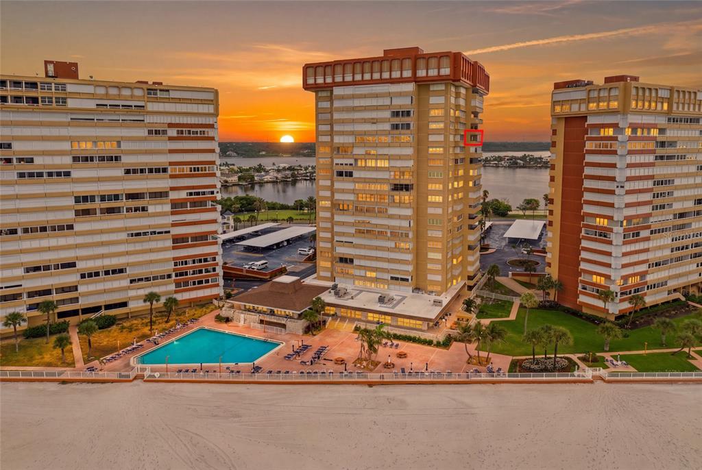 An aerial view of three high-rise apartment buildings and a swimming pool at sunset — 17920 GULF BOULEVARD UNIT 1502, ST PETERSBURG, FL
