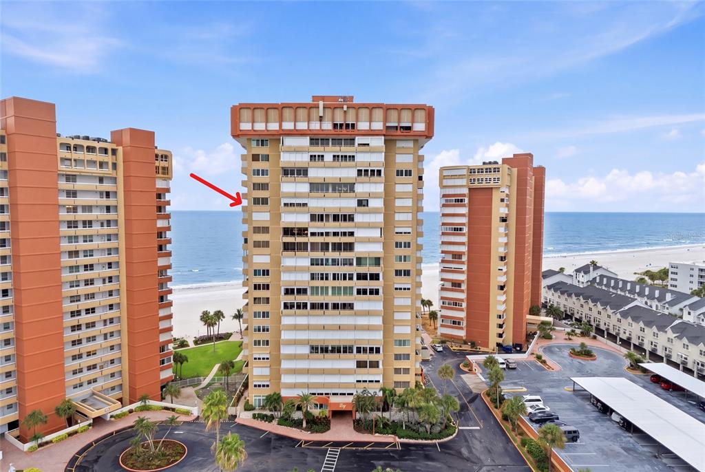 An aerial view shows three tall, orange-toned residential buildings situated along a sandy beach — 17920 GULF BOULEVARD UNIT 1502, ST PETERSBURG, FL