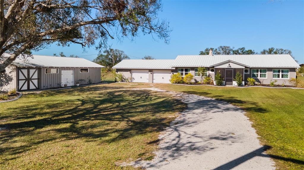 A single-story house with a metal roof and attached garage sits beside a detached shed — 2222 SE MCCLELLAND DRIVE, ARCADIA, FL