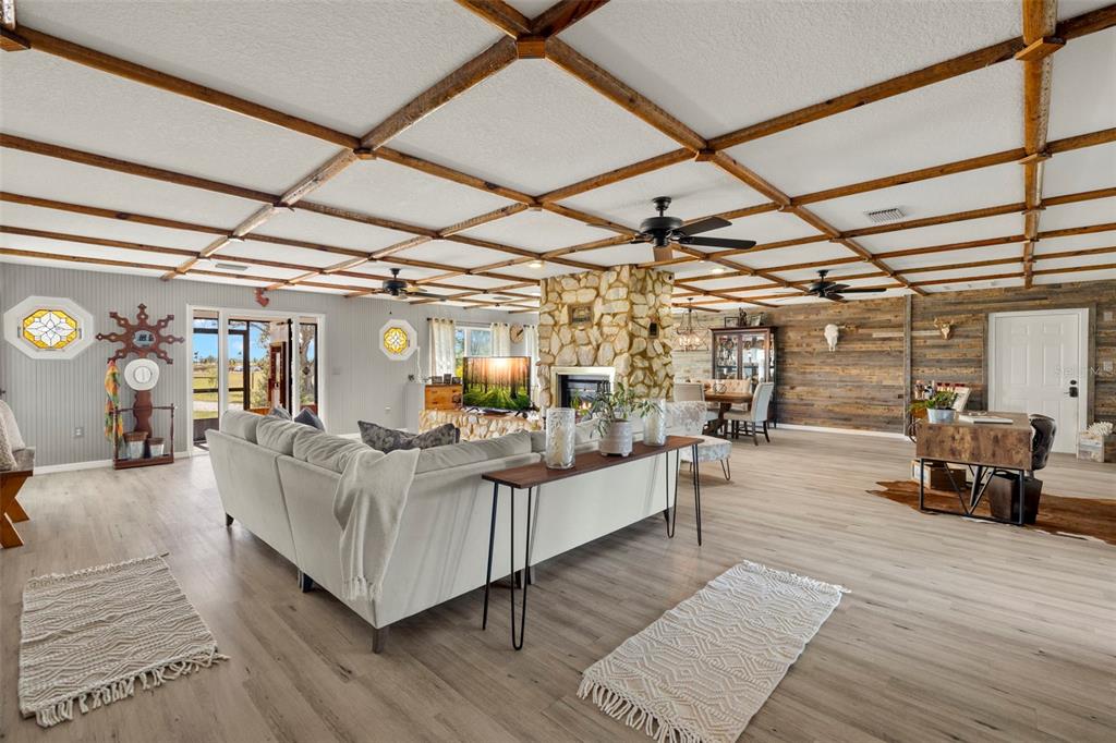 A spacious living room features a coffered wood ceiling, stone fireplace, and light wood flooring — 2222 SE MCCLELLAND DRIVE, ARCADIA, FL