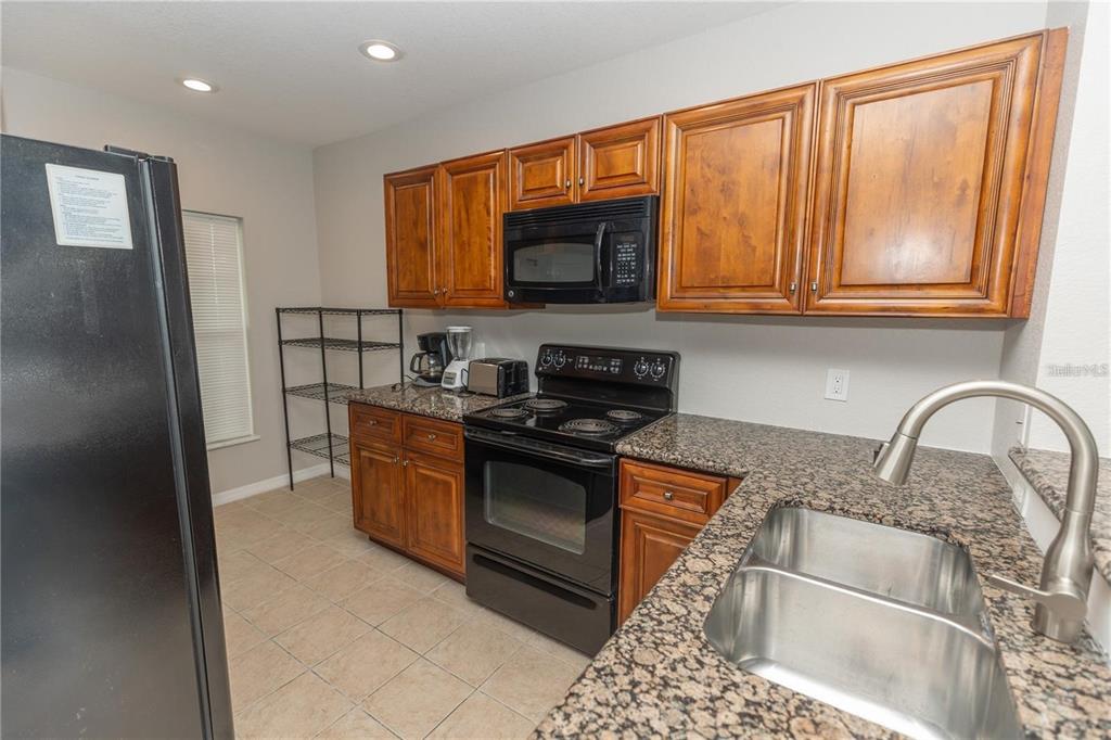 A kitchen features wood cabinets, granite countertops, black appliances, and a double-basin stainless steel sink — 8403 PLACIDA ROAD UNIT 303, PLACIDA, FL