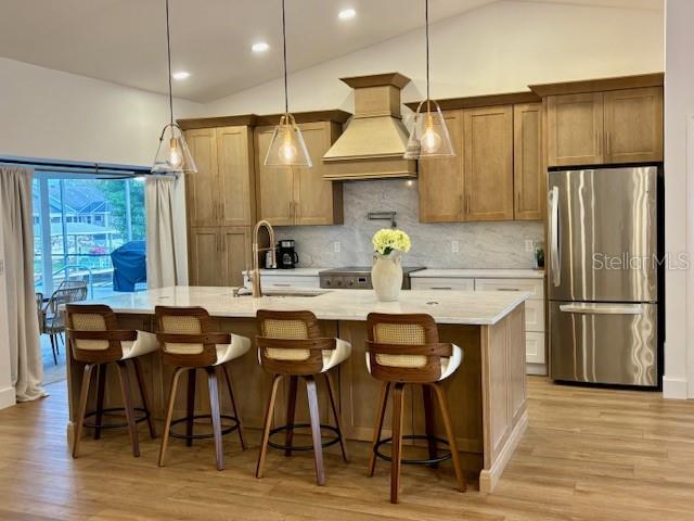 A kitchen features light wood cabinets, a marble backsplash, and four bar stools at an island — 13 COLONIA COURT, PALM COAST, FL