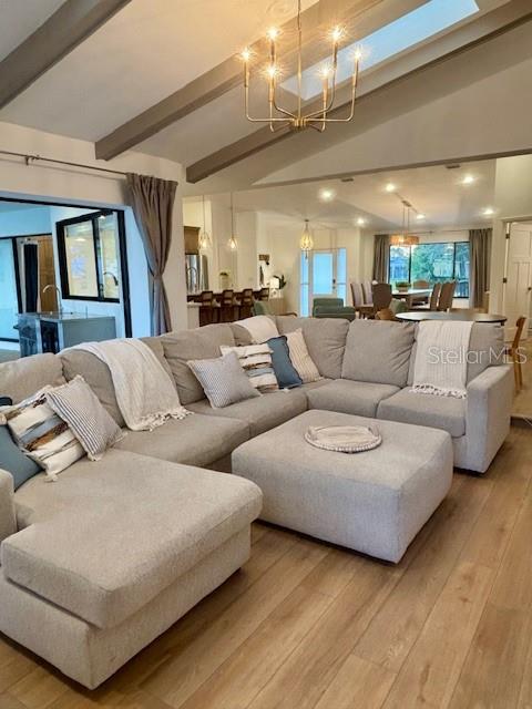 A spacious living room features a large sectional sofa, light wood flooring, and a chandelier — 13 COLONIA COURT, PALM COAST, FL