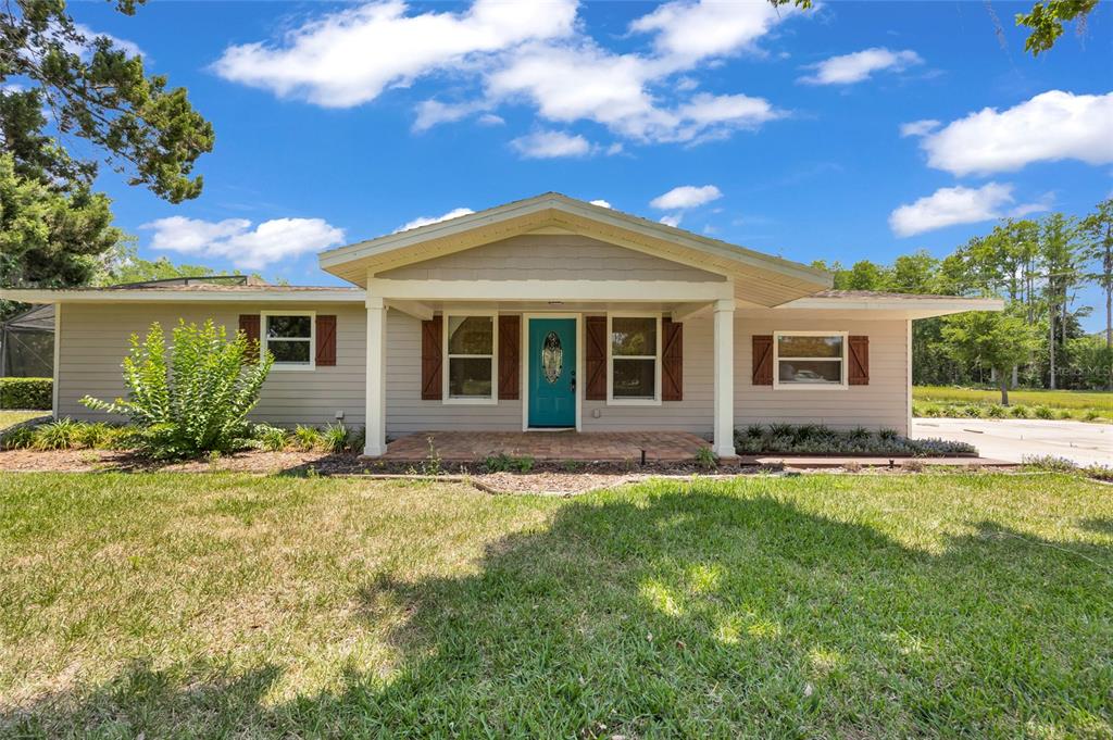 A single-story house with light siding, a teal front door, and a covered porch — 4125 RAMBLER AVENUE, ST CLOUD, FL