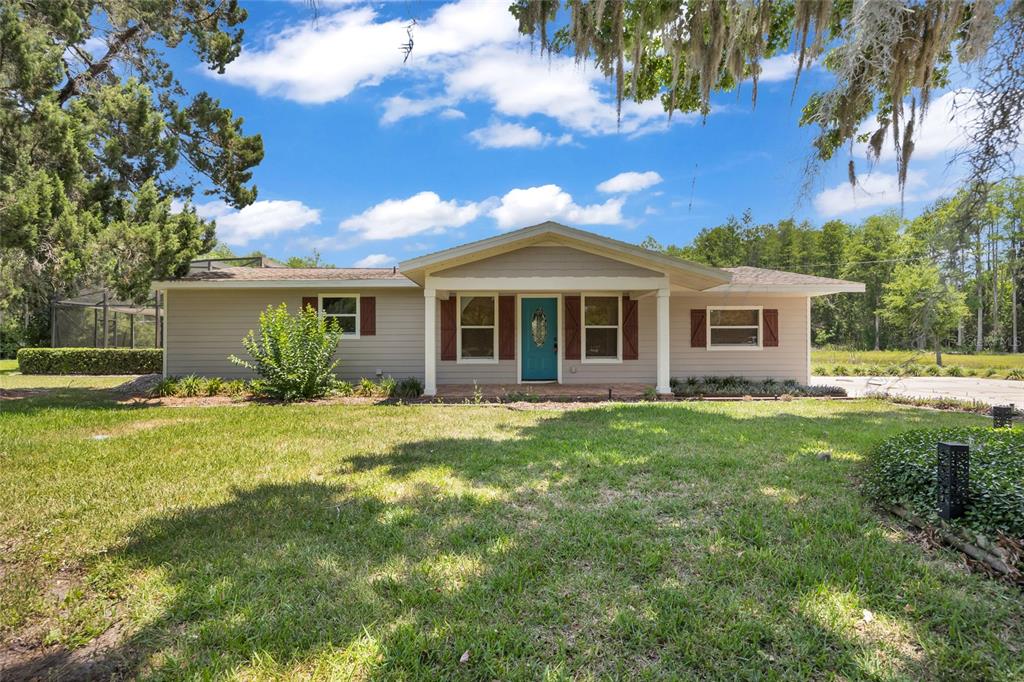 A single-story house with light siding, brown shutters, and a bright blue front door — 4125 RAMBLER AVENUE, ST CLOUD, FL