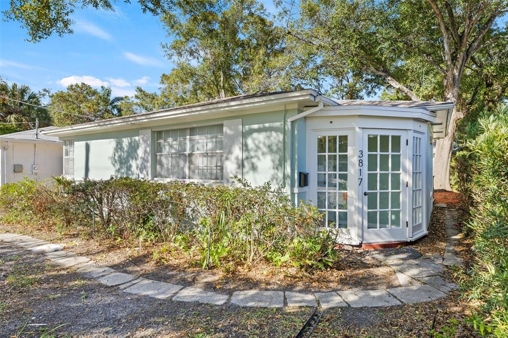 A light green house exterior features a white-framed glass entryway and a stone garden path — 3817 W BAY TO BAY BOULEVARD, TAMPA, FL