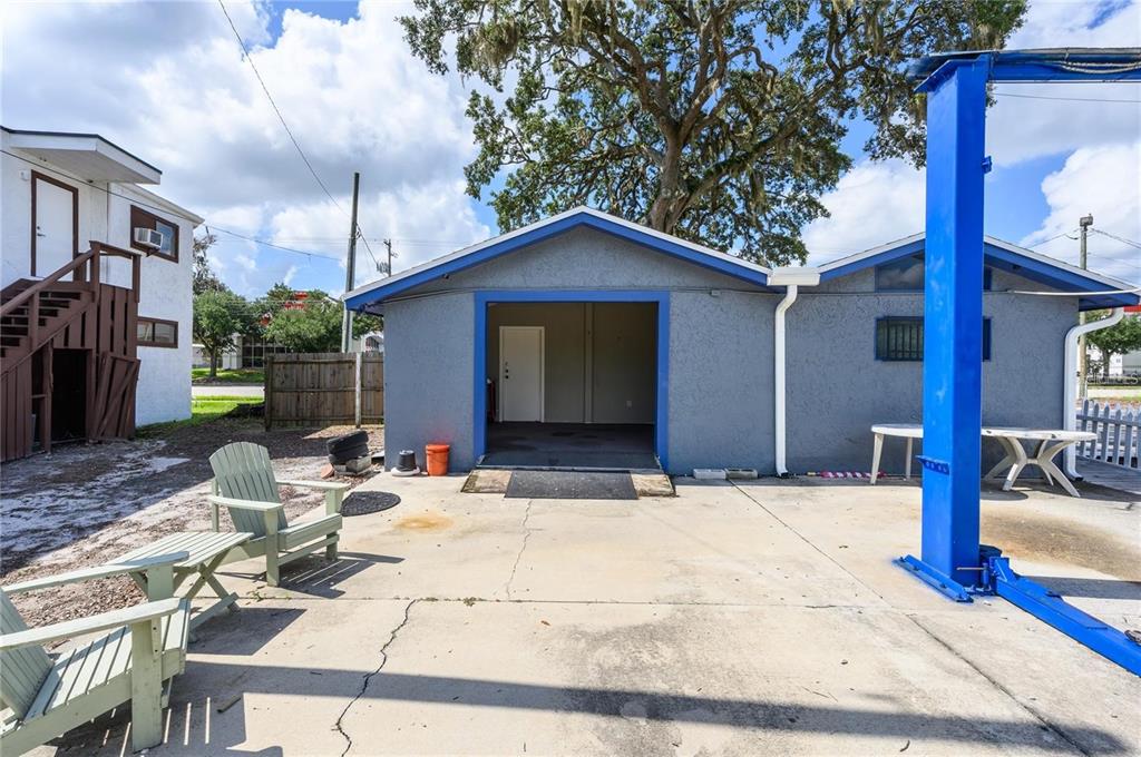 A concrete patio features a detached garage with a blue frame and a car lift — 377 E STATE ROAD 434, LONGWOOD, FL