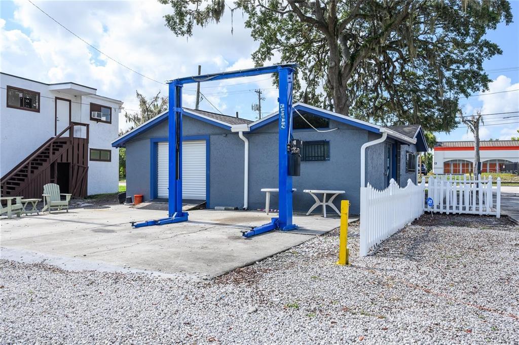 An outdoor vehicle lift stands on a concrete pad in front of a blue building — 377 E STATE ROAD 434, LONGWOOD, FL