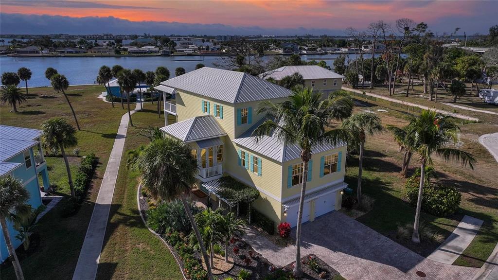 An aerial view of a yellow two-story house with a metal roof near the water — 6751 PORTSIDE LANE, ENGLEWOOD, FL