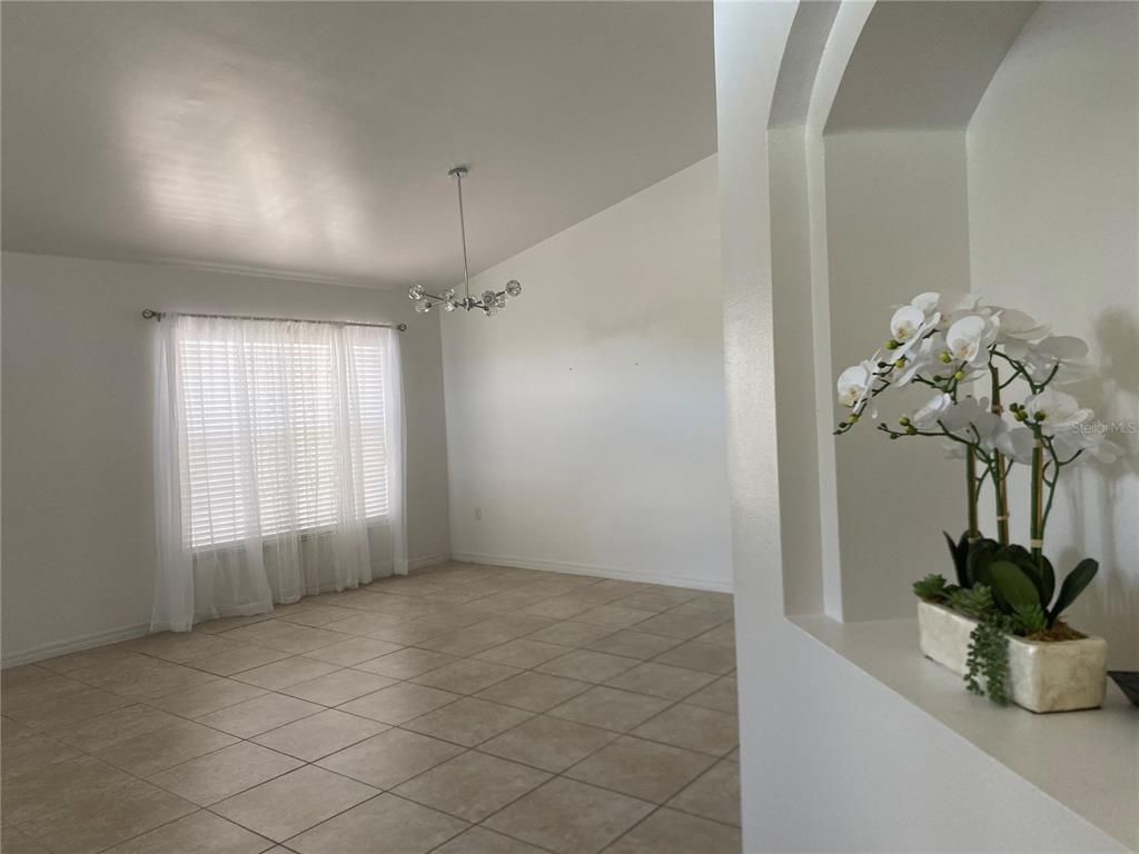 A dining room with tile flooring, a modern chandelier, and a large window with curtains — 419 BUCKINGHAM CIRCLE, DAVENPORT, FL