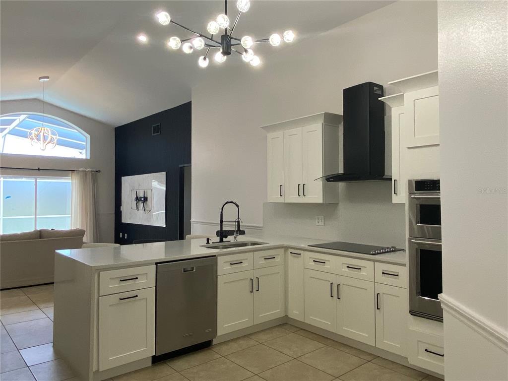 A modern kitchen features white cabinets, stainless steel appliances, and a central island with seating — 419 BUCKINGHAM CIRCLE, DAVENPORT, FL