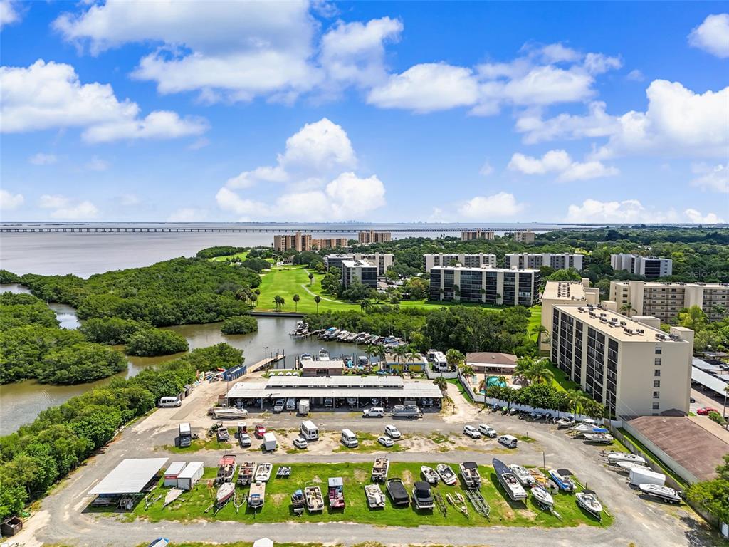 An aerial view shows a boat storage yard, apartment buildings, and a bridge over water — 900 COVE CAY DRIVE UNIT 2B, CLEARWATER, FL