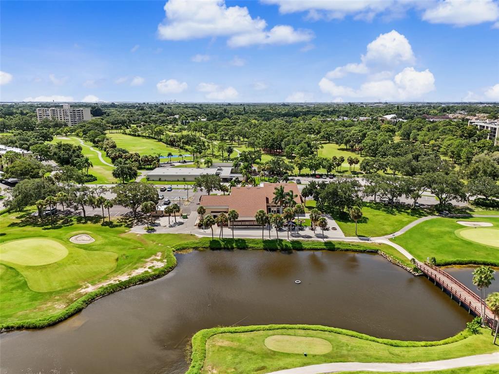 An aerial view shows a clubhouse building surrounded by a golf course and a pond — 900 COVE CAY DRIVE UNIT 2B, CLEARWATER, FL