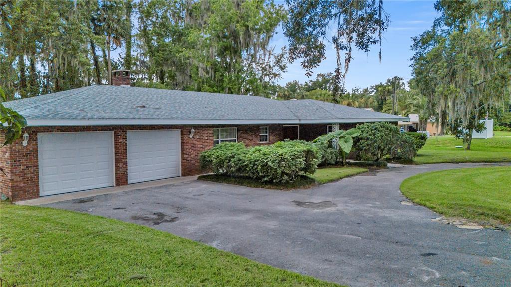 A single-story brick house with a two-car garage and a large paved driveway — 1940 ALICE DRIVE, ASTOR, FL