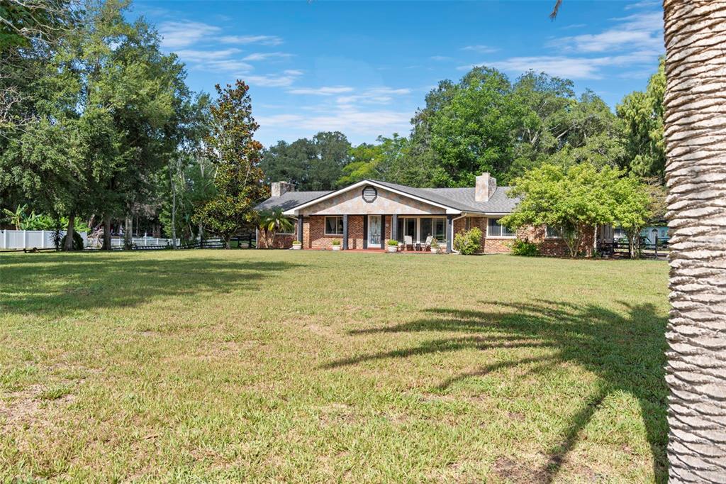 A single-story brick house with a gabled roof sits behind a large grassy lawn — 298-300 ORANGE AVENUE, ST CLOUD, FL
