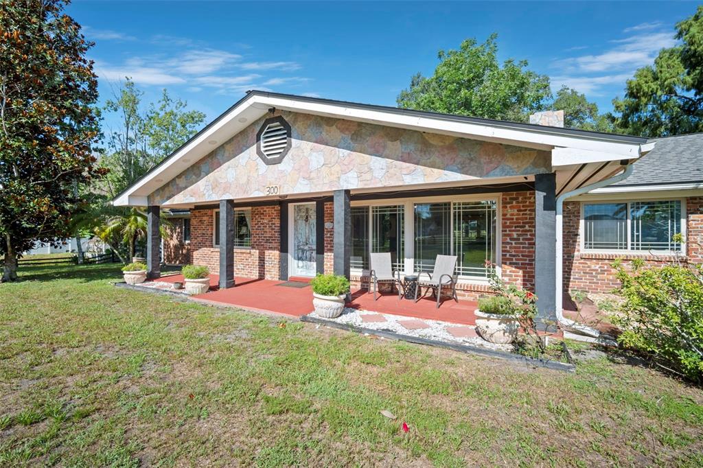 A single-story brick house features a stone-accented gable, a red porch, and large windows — 298-300 ORANGE AVENUE, ST CLOUD, FL