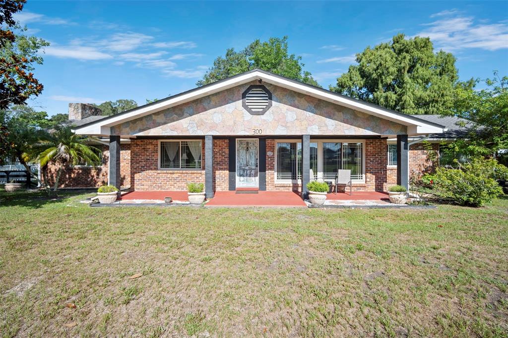 A single-story brick house with a stone-accented gable and a covered front porch — 298-300 ORANGE AVENUE, ST CLOUD, FL