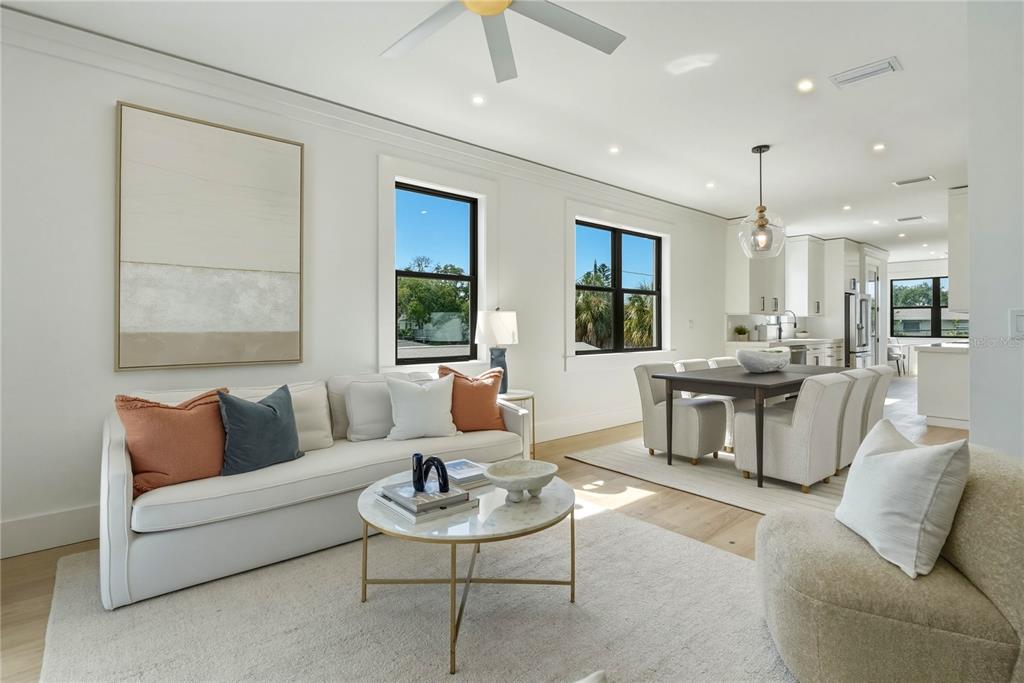 A bright, open-concept living and dining area features white walls, light wood floors, and modern furniture — 205 BATES AVENUE UNIT B, INDIAN ROCKS BEACH, FL