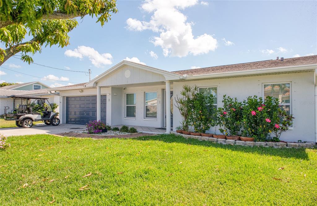 A single-story house with a white exterior, a two-car garage, and a golf cart parked — 551 CRYSTAL DRIVE, MADEIRA BEACH, FL
