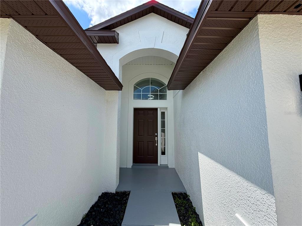 The exterior entrance features a dark brown door, an arched transom window, and white stucco walls — 13548 EYAS ROAD, ORLANDO, FL