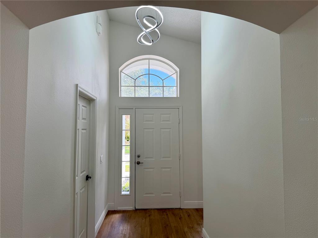 A bright entryway features a high vaulted ceiling, a modern light fixture, and a front door — 13548 EYAS ROAD, ORLANDO, FL