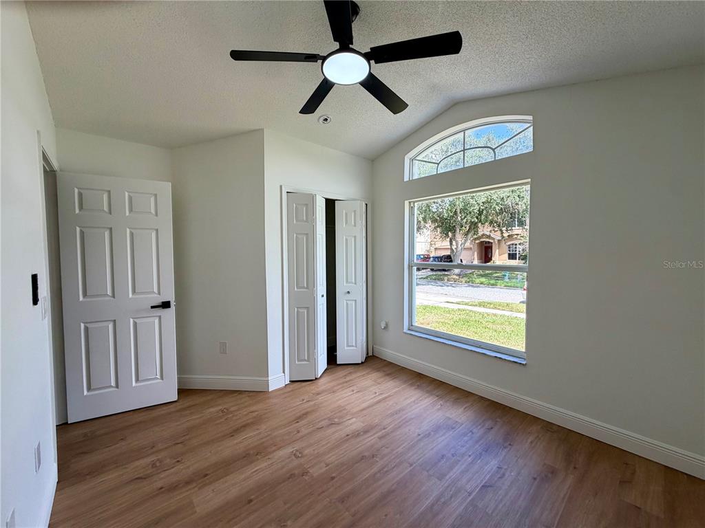 A bedroom with wood-look flooring, a ceiling fan, a closet, and a large arched window — 13548 EYAS ROAD, ORLANDO, FL