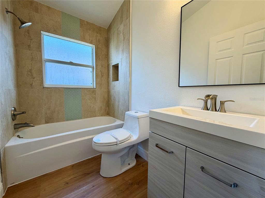 A bathroom features a tub-shower combo with tiled walls, a toilet, and a wood-look vanity — 13548 EYAS ROAD, ORLANDO, FL