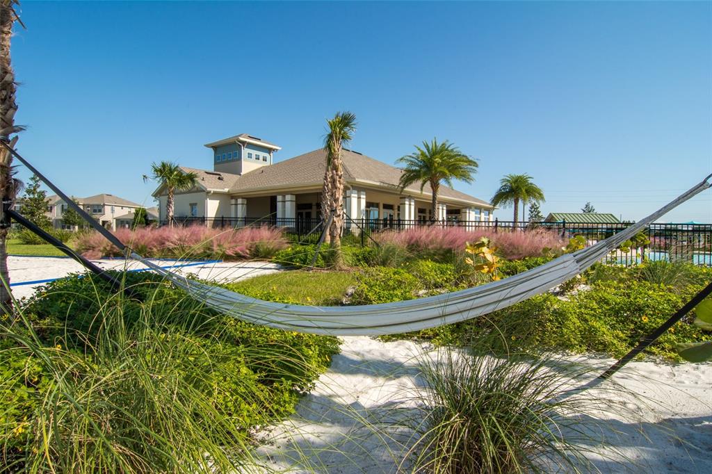A white hammock hangs in the foreground of a sandy area with a community clubhouse behind — 11881 SHINE VIEW LANE, WINTER GARDEN, FL