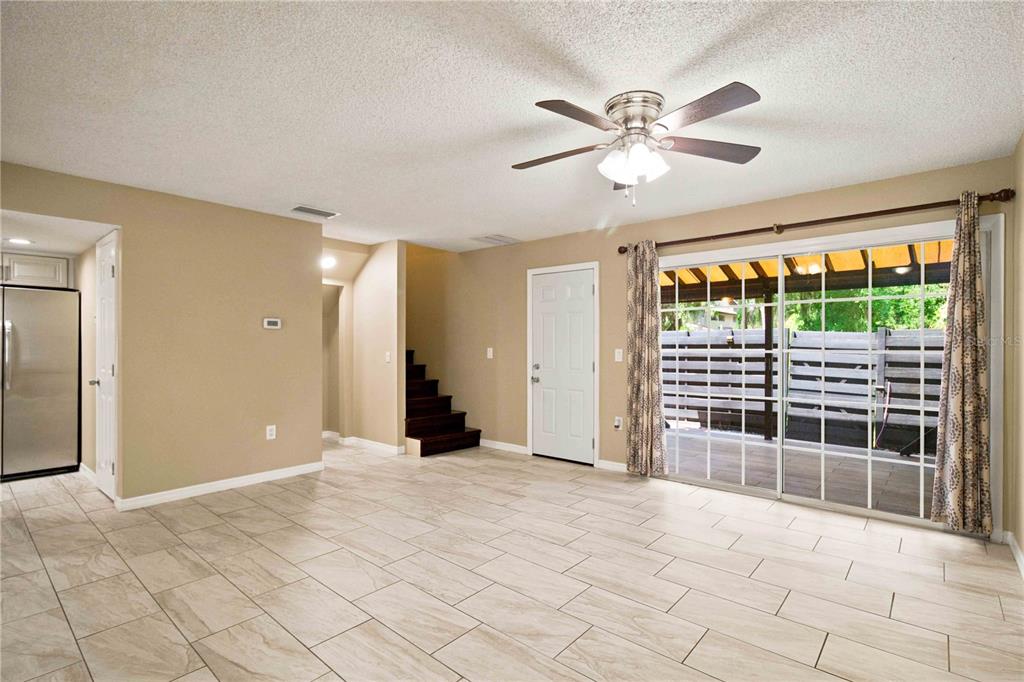 A living room with tile flooring, a ceiling fan, stairs, and sliding glass patio doors — 1006 LONGFELLOW COURT, SARASOTA, FL