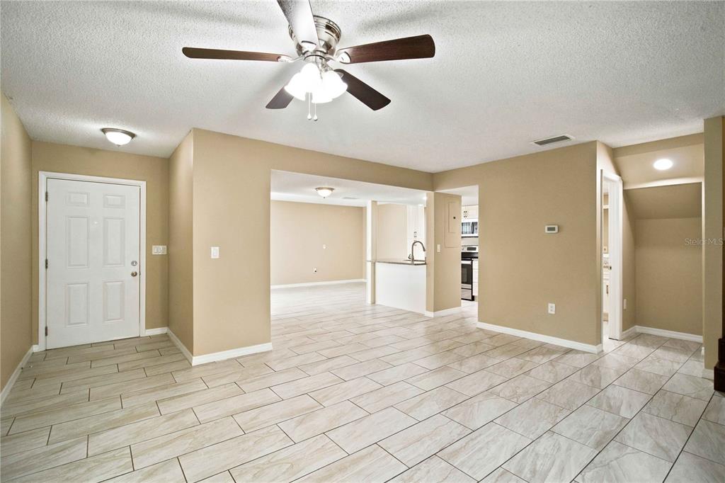 An open-concept living area features light-colored tile flooring, beige walls, and a ceiling fan — 1006 LONGFELLOW COURT, SARASOTA, FL