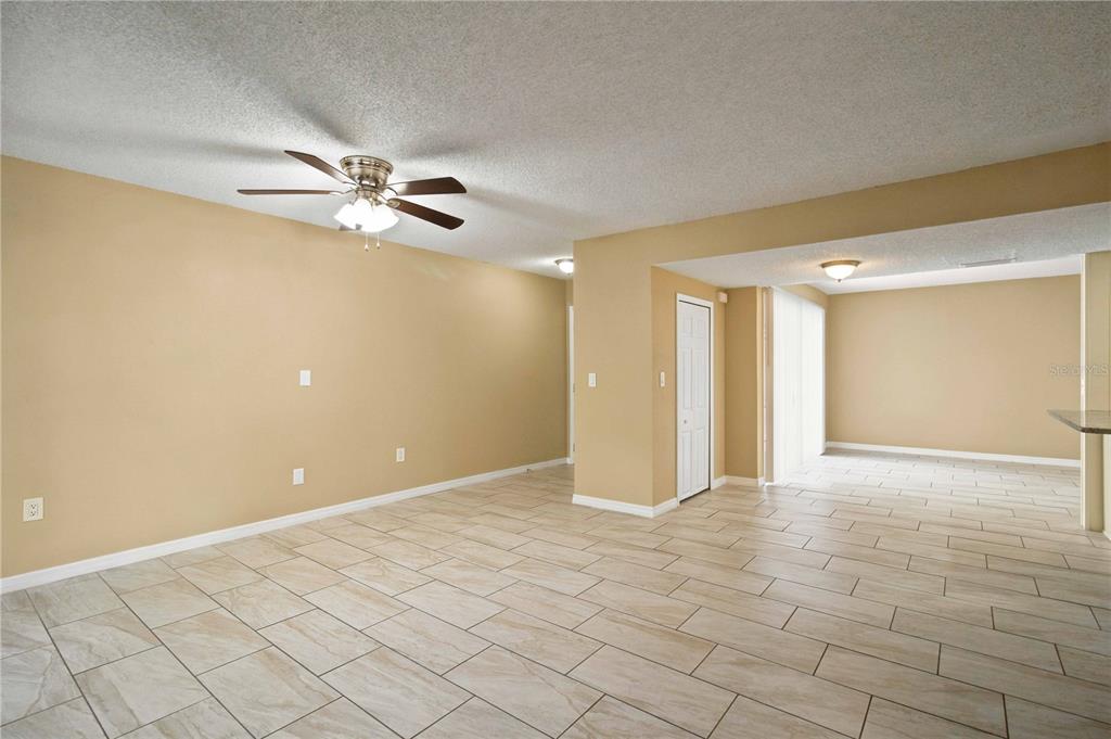 An open-concept living area features beige walls, a ceiling fan, and light-colored tiled flooring — 1006 LONGFELLOW COURT, SARASOTA, FL
