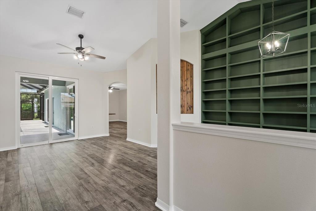 A living area features wood-look flooring, a sliding glass door, and a green built-in bookshelf — 12211 23RD STREET E, PARRISH, FL
