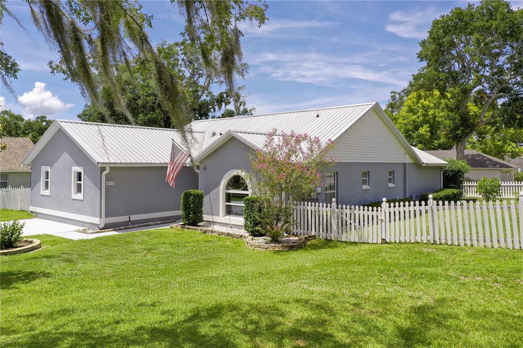 A single-story gray house with a metal roof and a white picket fence — 1050 FAHNSTOCK STREET, EUSTIS, FL